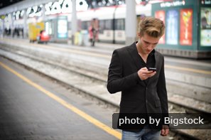 Young man on train platform with cell phone